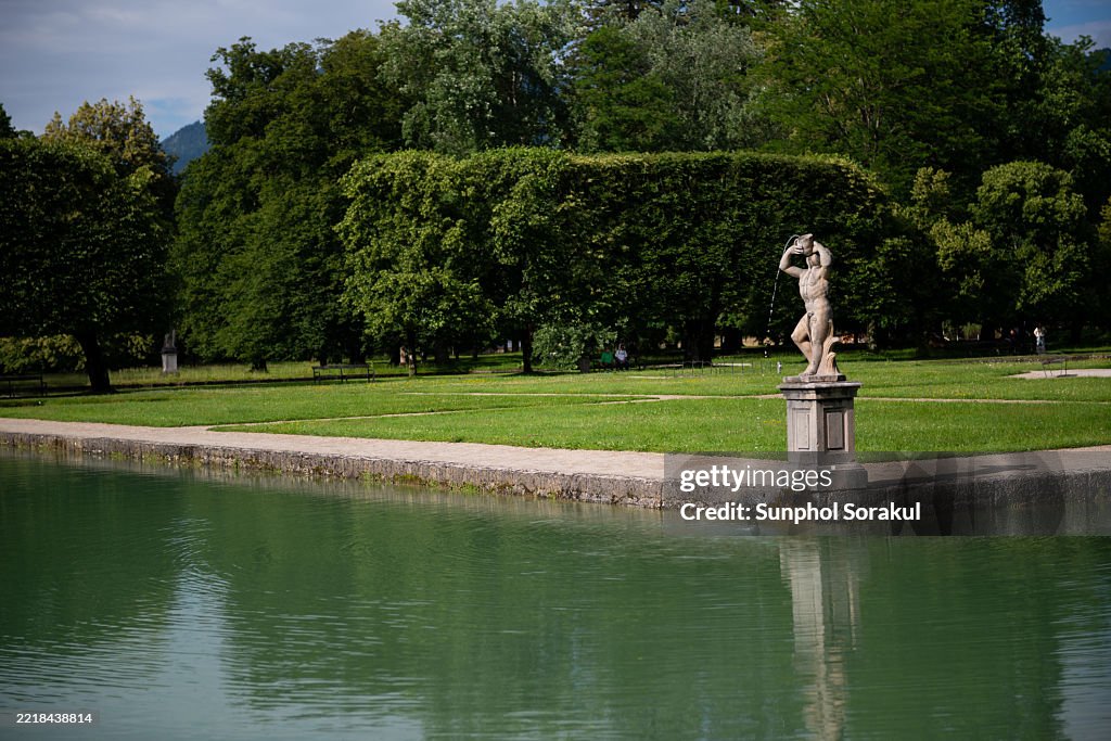 The reflection pond and elegant sculptures create a tranquil scene within the gardens of Schloss Hellbrunn in Salzburg, Austria.