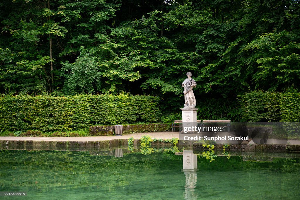 The reflection pond and elegant sculptures create a tranquil scene within the gardens of Schloss Hellbrunn in Salzburg, Austria.