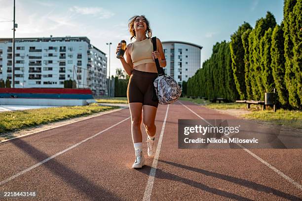 junge frau, die an einem sonnigen tag auf einem outdoor-weg geht - athleisure stock-fotos und bilder