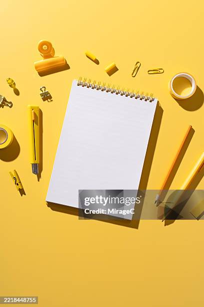 blank notebook with yellow stationery on yellow background - bloco espiral imagens e fotografias de stock