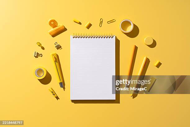blank notebook with yellow stationery on yellow background - instrumento de escribir fotografías e imágenes de stock