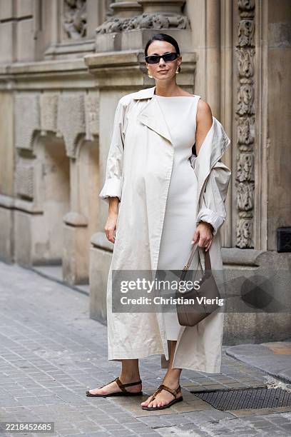 Zina Charkoplia wears white sleeveless Almada dress, The Frankie Shop creme white trench coat, brown YSL bag and YSL sandals, sunglasses, golden...
