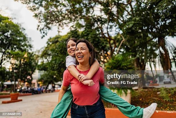 mother and daughter doing piggyback outdoors - mannerism stock pictures, royalty-free photos & images