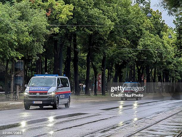 Austrian police vehicles with flashing blue lights drive on wet roads near Weihburggasse and Stadtpark in Vienna, Austria, on June 7, 2025.