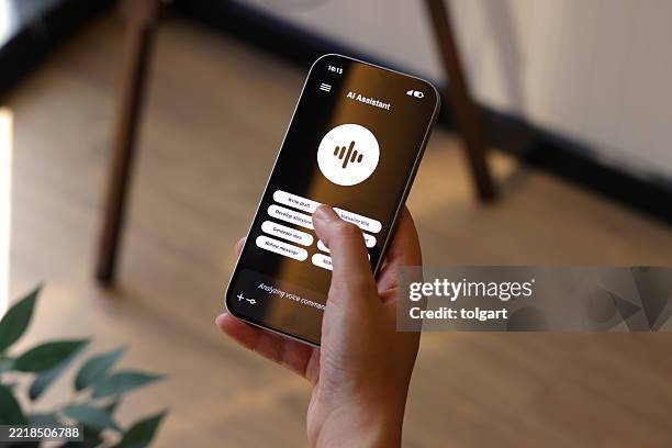 ai voice assistant interface on smartphone screen held indoors - speech recognition stock pictures, royalty-free photos & images