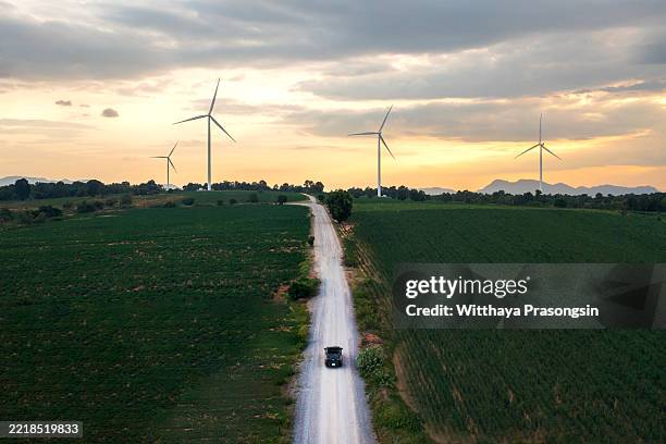 driving towards sustainability: car on a country road with wind turbines at sunset - emissioni di co2 foto e immagini stock