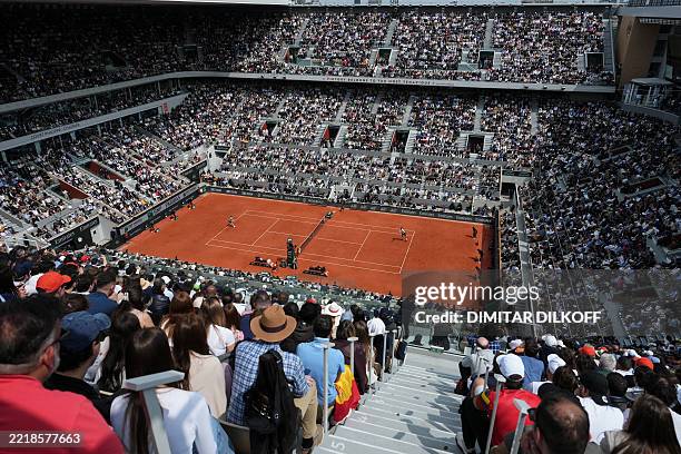 Spectators watch the men's singles final match between Spain's Carlos Alcaraz and Italy's Jannik Sinner on day 15 of the French Open tennis...