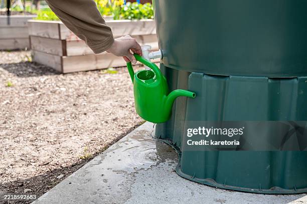 hand filling watering can from rainwater tank - vorratstank stock-fotos und bilder