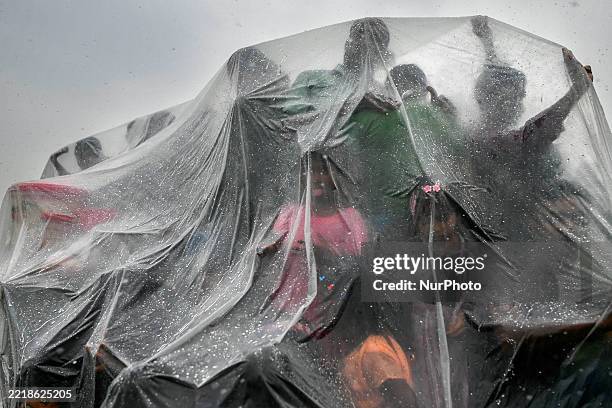 Villagers cover themselves with polythene during rain as they attend a traditional horse racing competition in a rural area of Magura District,...