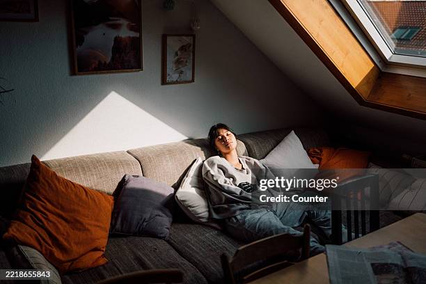 teenage girl enjoying peaceful moment relaxing on a cozy couch in a sunlit room - gen z stock-fotos und bilder