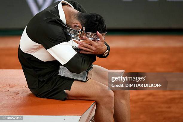 Spain's Carlos Alcaraz embraces the trophy on the podium after winning the men's singles final match against Italy's Jannik Sinner on day 15 of the...