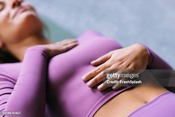 woman relaxing with hand on chest practicing mindfulness in purple outfit - fisiologia imagens e fotografias de stock