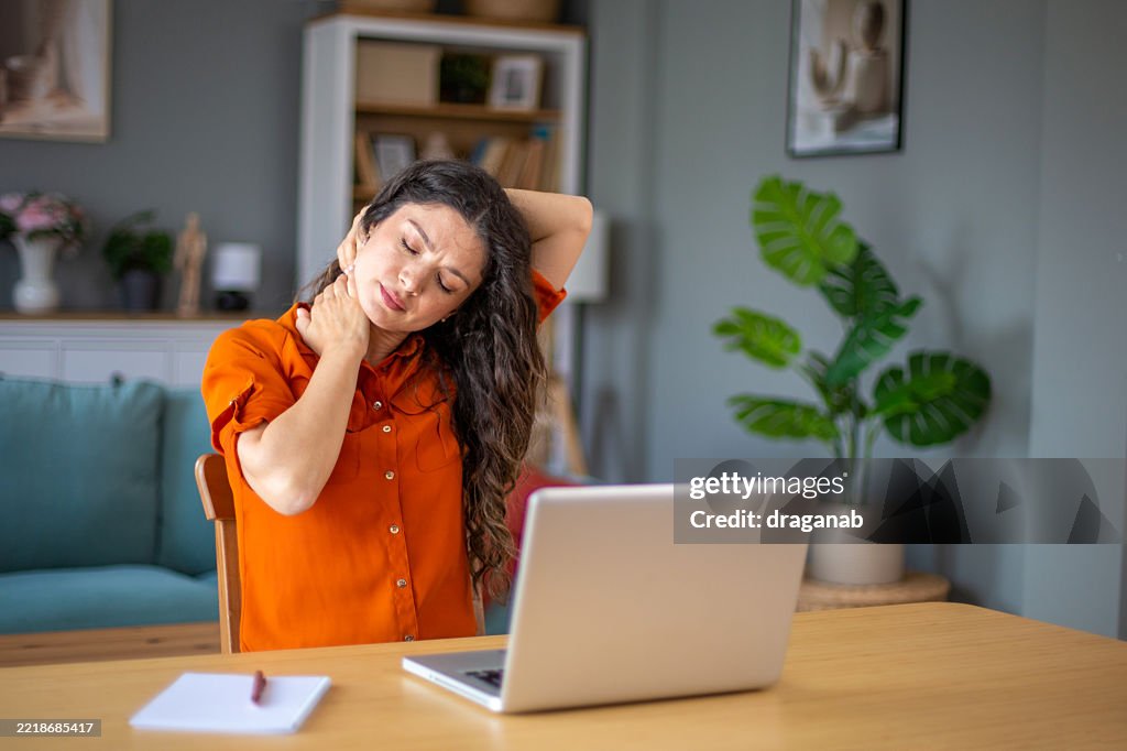 Young woman working from home suffering from neck pain