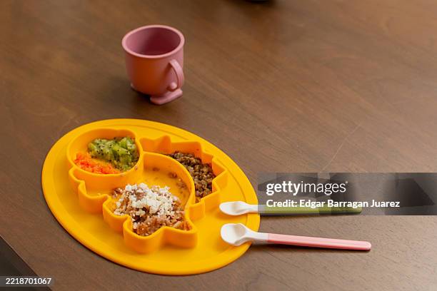 baby food on dinosaur shaped plate with spoons and cup - fruit puree stock pictures, royalty-free photos & images