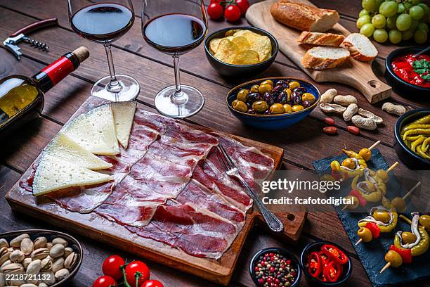 mesa llena de aperitivos: jamón, queso, vino tinto y encurtidos. tapas típicas españolas - jamón ibérico fotografías e imágenes de stock