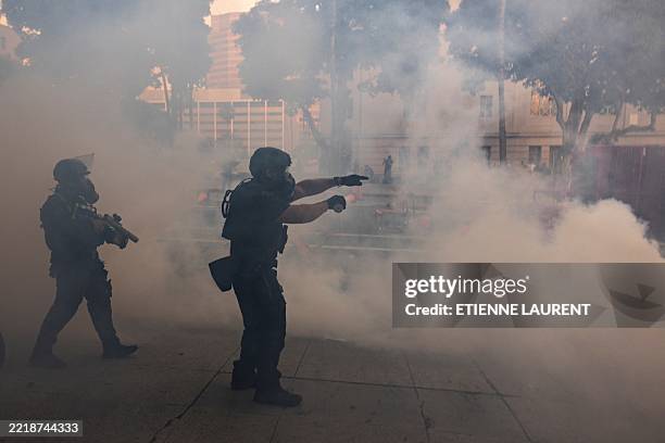 Los Angeles police officers advance on a makeshift barricade in a cloud of tear gas as clashes erupt with demonstrators next to City Hall during a...