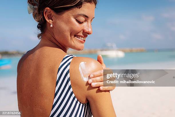 woman applying sun cream on tropical beach - sun cream stock pictures, royalty-free photos & images