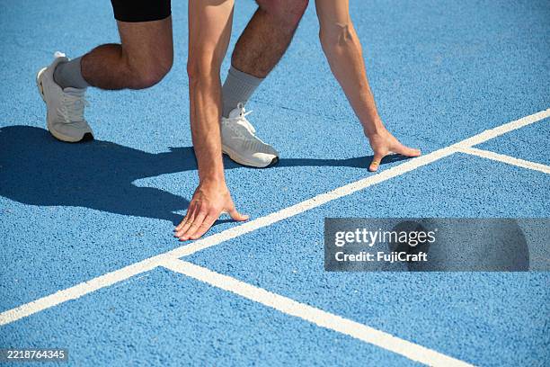 corridore che si prepara per una gara su una pista blu - linea di partenza attrezzatura sportiva foto e immagini stock