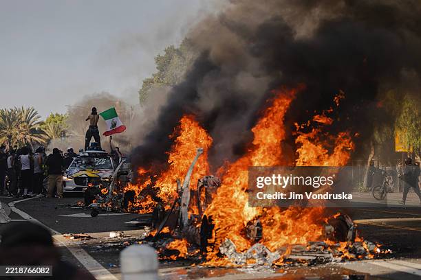 Several cars burn on North Los Angeles street during clashes between protesters and police on June 8, 2025 in Downtown Los Angeles, California. The...