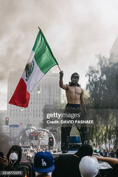 Waymo Flag A protester waves a Mexican flag while standing on a vandalized Waymo ...