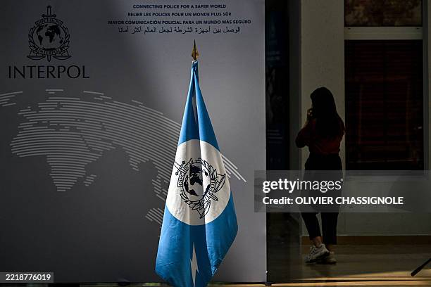 Woman walks near an Interpol flag ahead at the International Criminal Police Organisation Interpol headquarters in Lyon, eastern France, on June 9,...