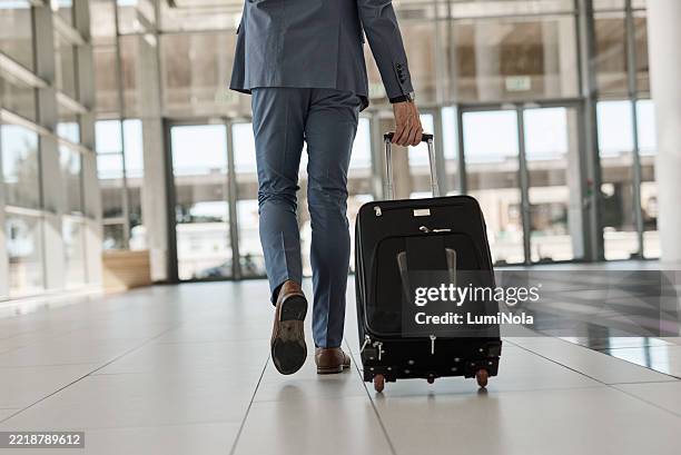 businessman walking through airport terminal with suitcase - wheeled luggage stock pictures, royalty-free photos & images