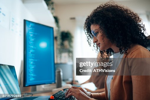 Hispanic Woman engineer analyzing and debugging code on large screen in collaborative workspace Hispanic Woman engineer analyzing and debugging code on large screen in collaborative workspace