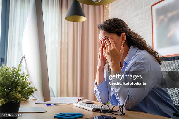 tired woman touching her eyes while working on computer. eye fatigue - rubbing eyes stock pictures, royalty-free photos & images