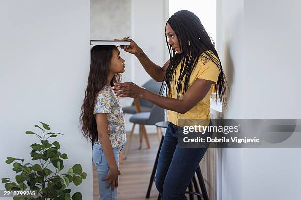 mother measuring her daughter's height - growth chart stock pictures, royalty-free photos & images
