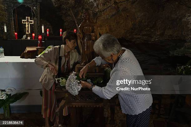 Two local residents decorate the statue of the Virgin with flowers inside the rock-cut hermitage of Santa Justa before taking it out in the Santa...