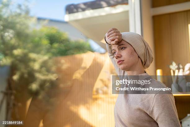 young cancer patient feeling sick and looking out the window - laubsäge stock-fotos und bilder