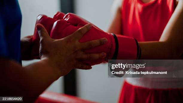 young asian man helping a female boxer put on hand wraps while preparing for a boxing match. - gants de sport photos et images de collection
