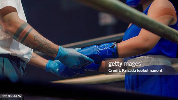 asian boxing referee inspecting a contestant's gloves before a match started. - boxing arena stock pictures, royalty-free photos & images