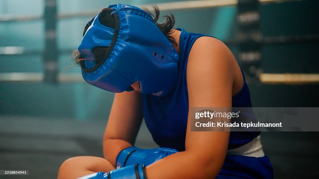 Young Asian woman feeling disappointed and tired after losing a boxing match.