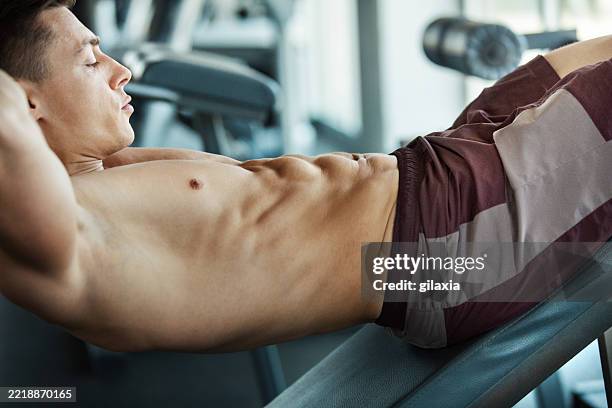 young man doing sit-ups in a gym - weight bench stock pictures, royalty-free photos & images