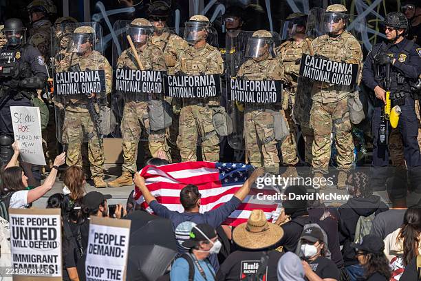 Protesters confront California National Guard soldiers and police outside of a federal building as protests continue in Los Angeles following three...