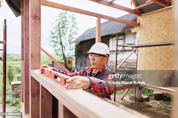 constructeur expérimenté utilisant le niveau à bulle pour vérifier l’alignement sur le chantier de construction d’une maison à ossature - male using spirit level photos et images de collection