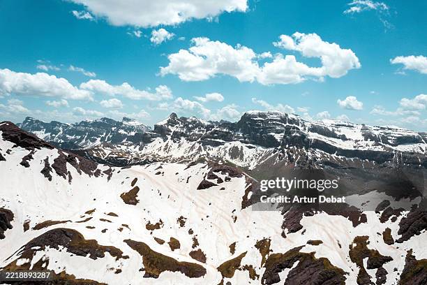 snow covered peaks of the sierra de alano in the pyrenees — aerial view highlighting late spring snowpack and mountain water reserves in aragon, spain - pirineos fotografías e imágenes de stock