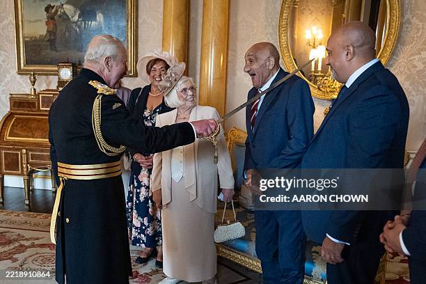 Former Rugby League player Billy Boston is Knighted by Britain's King Charles III during an Investiture ceremony at Buckingham Palace in London on...