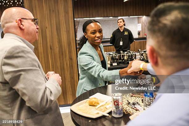 Morgan Taylor, of Freeport, New York, vice president of business operations for both the Long Island Nets and New York Liberty, center, shakes hands...