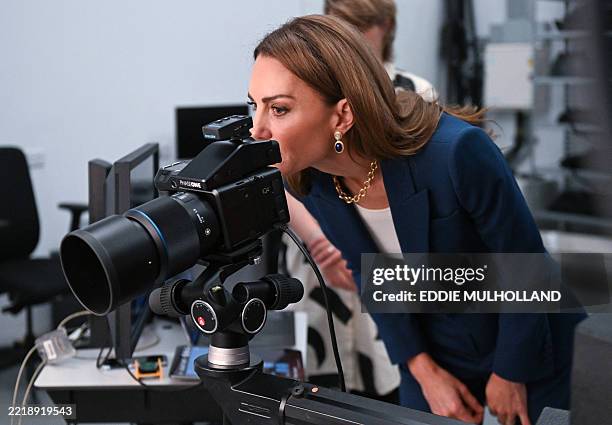 Britain's Catherine, Princess of Wales looks through the viewfinder of a camera in the photographic studio during a visit to the V&A East Storehouse,...