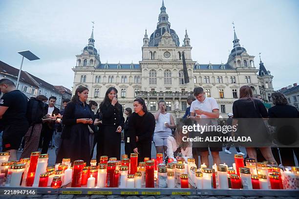 People light candles at a makeshift memorial site after several people died in a school shooting, on June 10, 2025 in Graz, southeastern Austria....