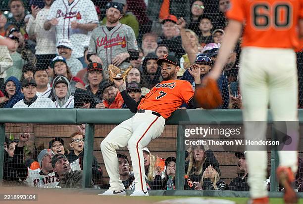 First baseman Dominic Smith of the San Francisco Giants collides with the rail as he catches a foul pop-up hit by Austin Riley of the Atlanta Braves...