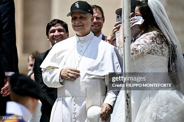Pope Leo XIV reacts wearing a Chicago White Sox baseball team cap as he meets newly wedded couples during the weekly general audience in St Peter's...