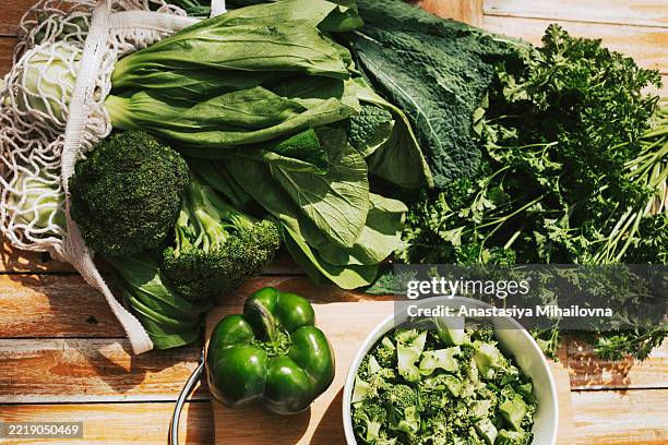 fresh lettuce leaves, cayla, green pepper and broccoli on a wooden table. farm greens and vegetables for cooking - couve imagens e fotografias de stock