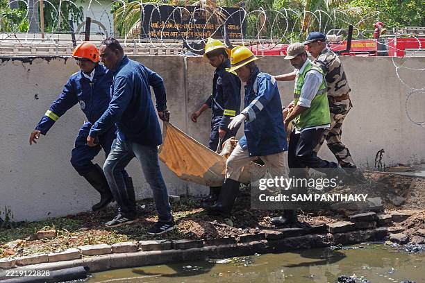 Firefighters carry a victim's body after the Air India flight 171 crashed in a residential area near the airport in Ahmedabad on June 12, 2025. The...