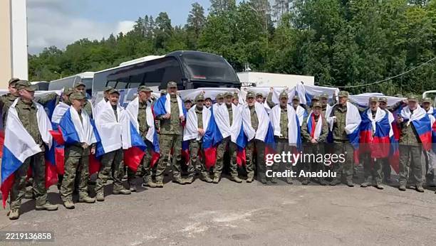 Screen grab taken from a video shows Russian soldiers draped in national flags after being released as part of a prisoner exchange between Russia and...