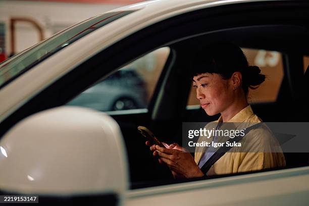 woman using smartphone inside car in parking lot - location tracking stock pictures, royalty-free photos & images