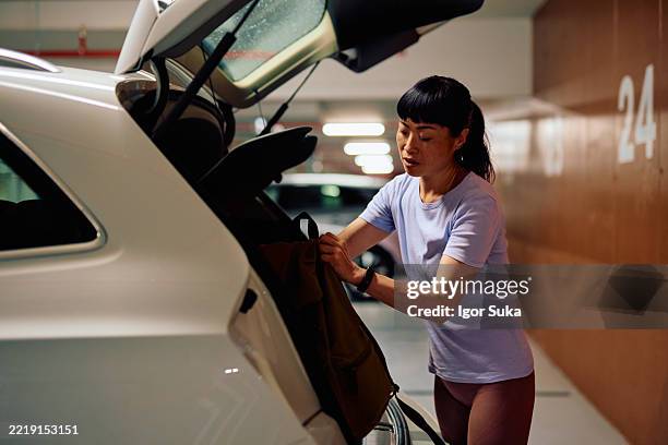 woman putting gym bag in car trunk after workout - car trunk closed stock pictures, royalty-free photos & images