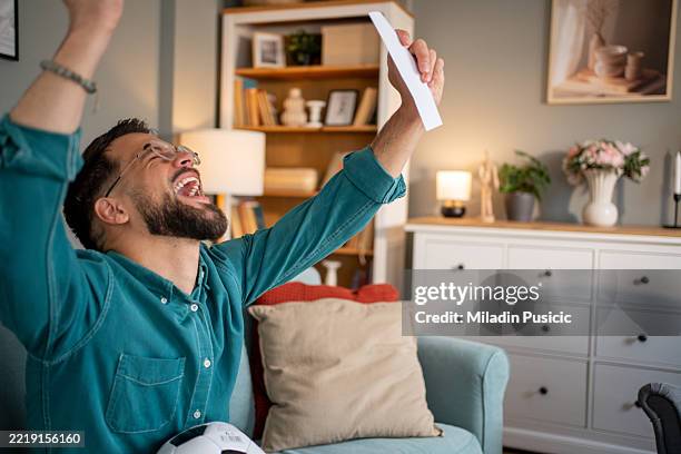 fan de sport excité célébrant le pari gagnant sur le match de football à la maison - loto photos et images de collection
